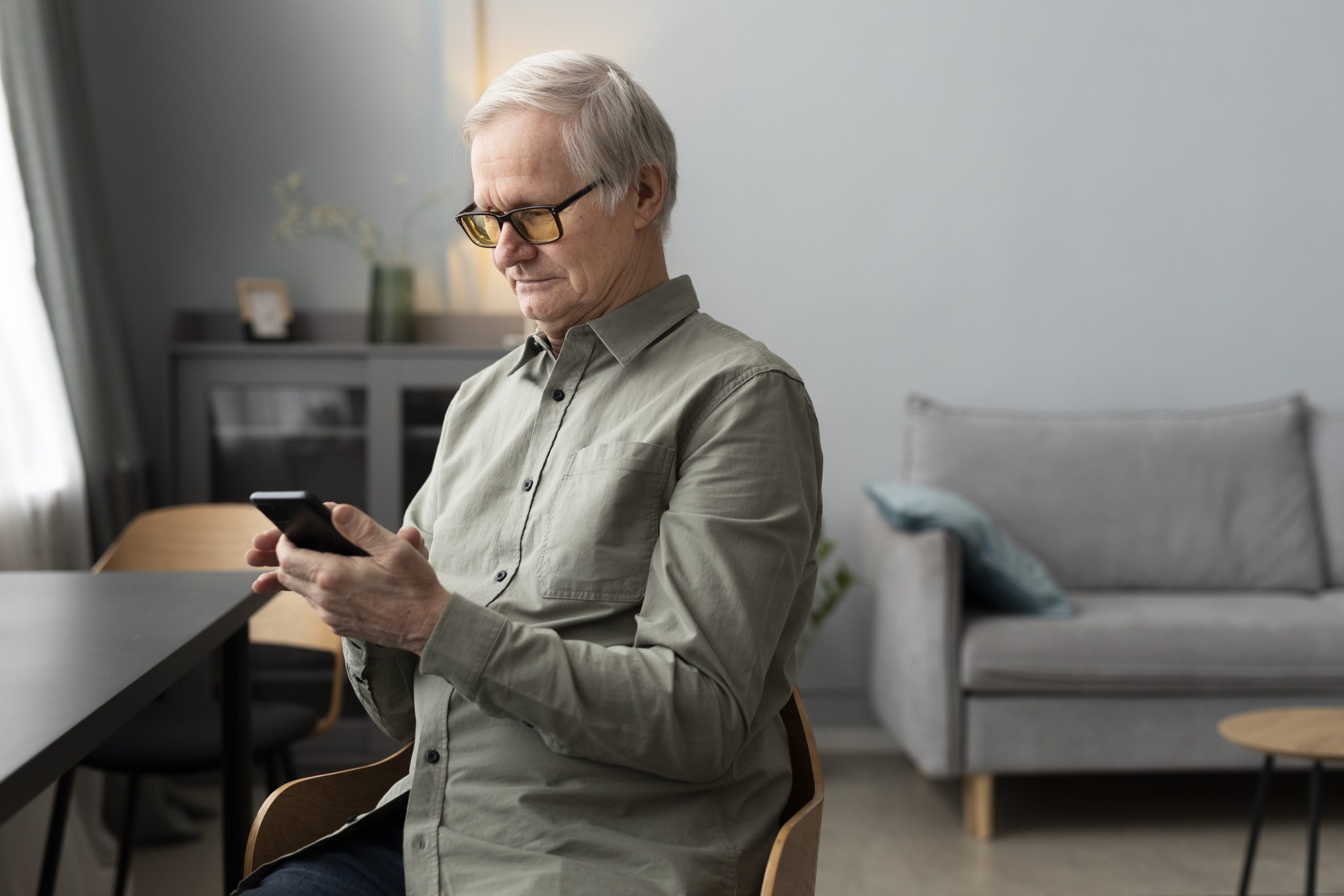 happy-senior-man-using-smartphone-living-room-modern-apartment